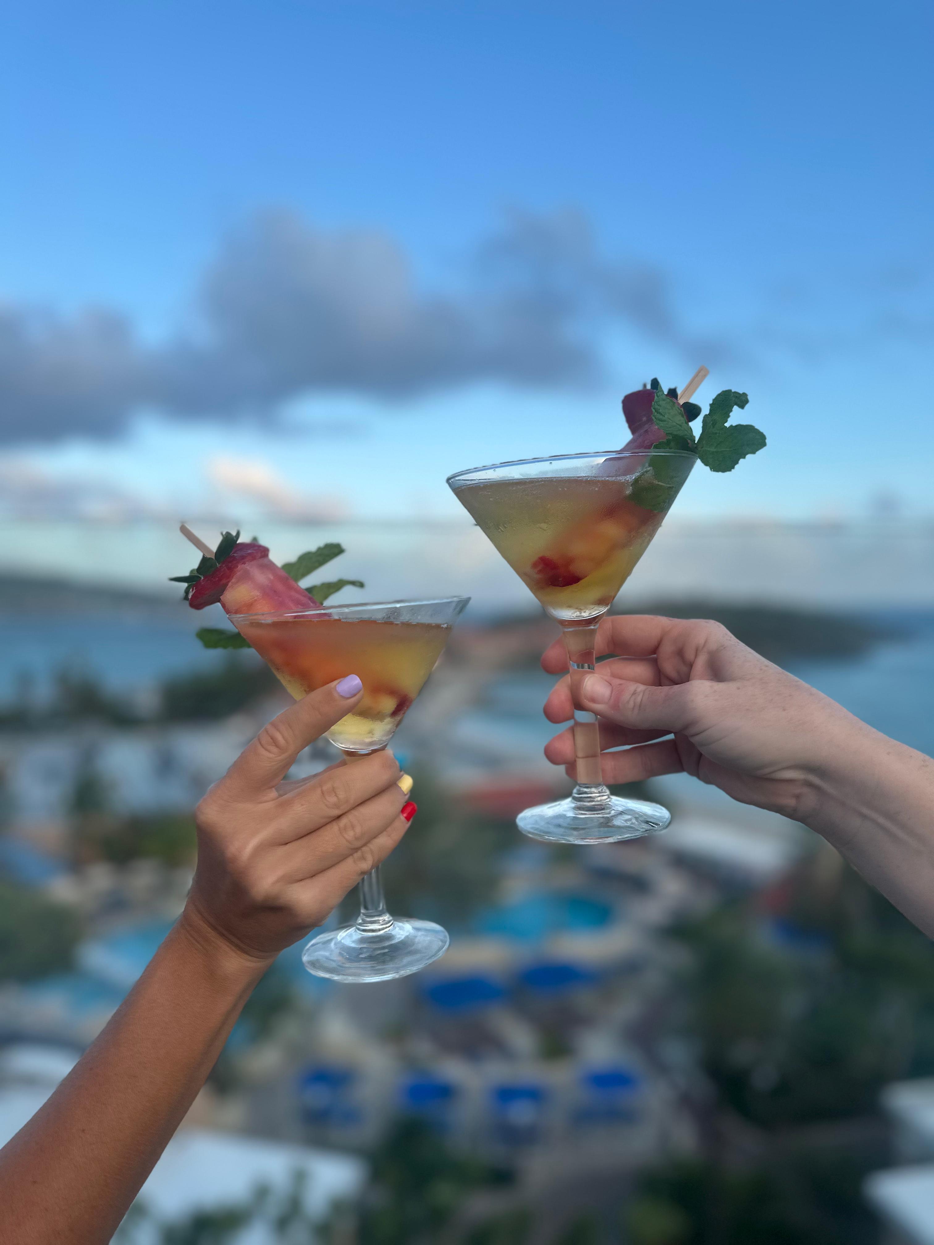 a pair of hands holding up a glass of drinks